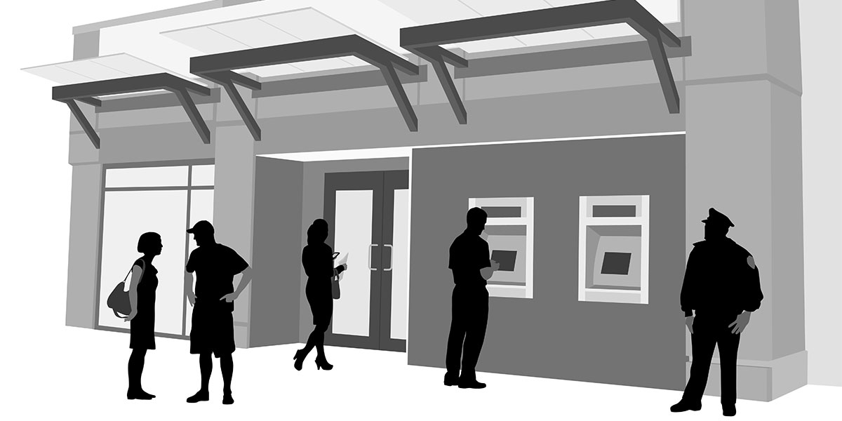 Figures in silhouette standing in front of a bank of ATMs